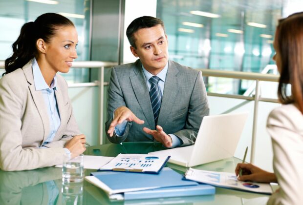 Females and male business professionals having discussion in an office meeting room.